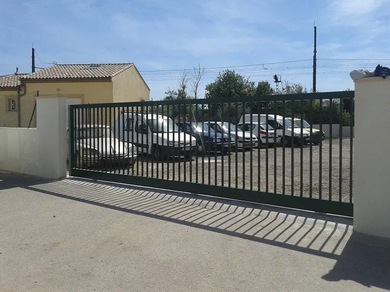 Otopark girişinde siyah metal kayar bahçe kapısı